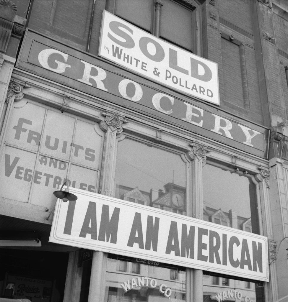 I Am an American' posted above a grocery store, Oakland, 1942.