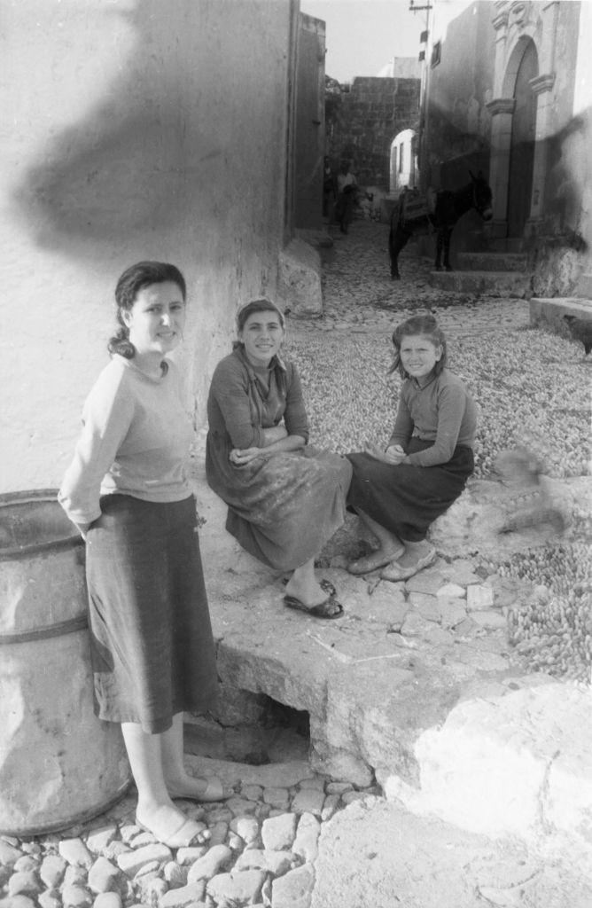 Three young girls talk outside a house on Rhodes, Greece, 1950s.