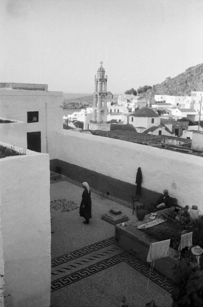 A woman on a roof terrace in the town of Lindos looking towards the Panagia Church on Rhodes, Greece, 1950s.