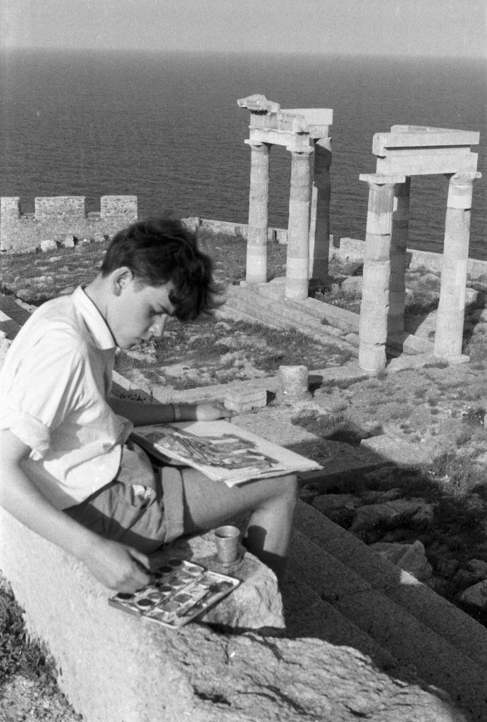 A young man paints the temple ruins of Ialyssos on Rhodes in Greece, 1950s.