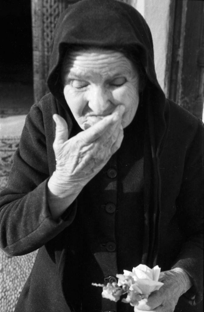 An old woman ties flowers in Greece, 1950s.