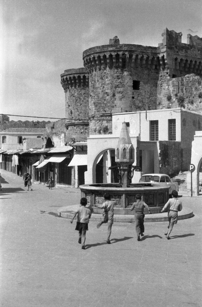 Children run to play to a fountain in Rhodes, Greece, 1950s.