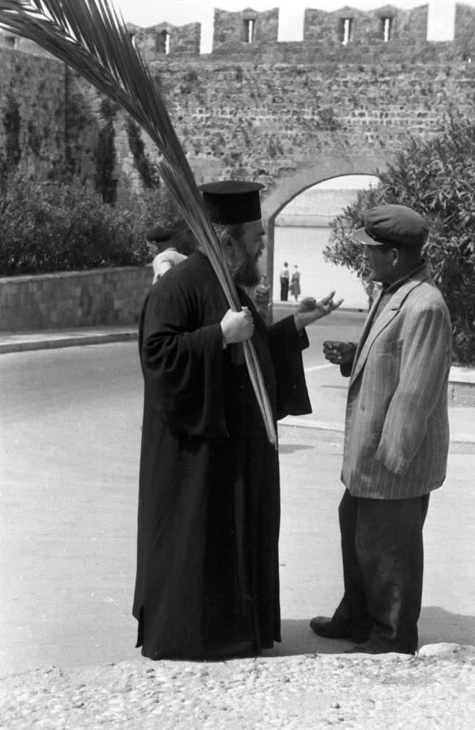 A passer-by speaks probably on Palm Sunday with a clergyman in Rhodes, Greece, 1950s.
