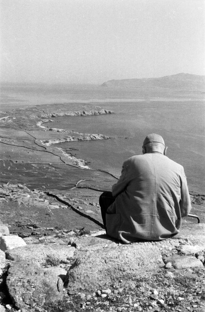 A man sits above the temple ruins of Ialyssos on Rhodes and looks out over the sea and the neighboring islands, Greece, 1950s.