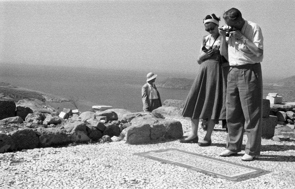 Tourists photograph a mosaic inscription on the floor of the temple complex of Ialyssos in Rhodes, Greece, 1950s.