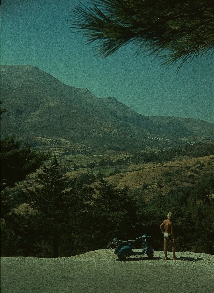 Man with scooter on Rhodes Island with mountains in background, 1970s.
