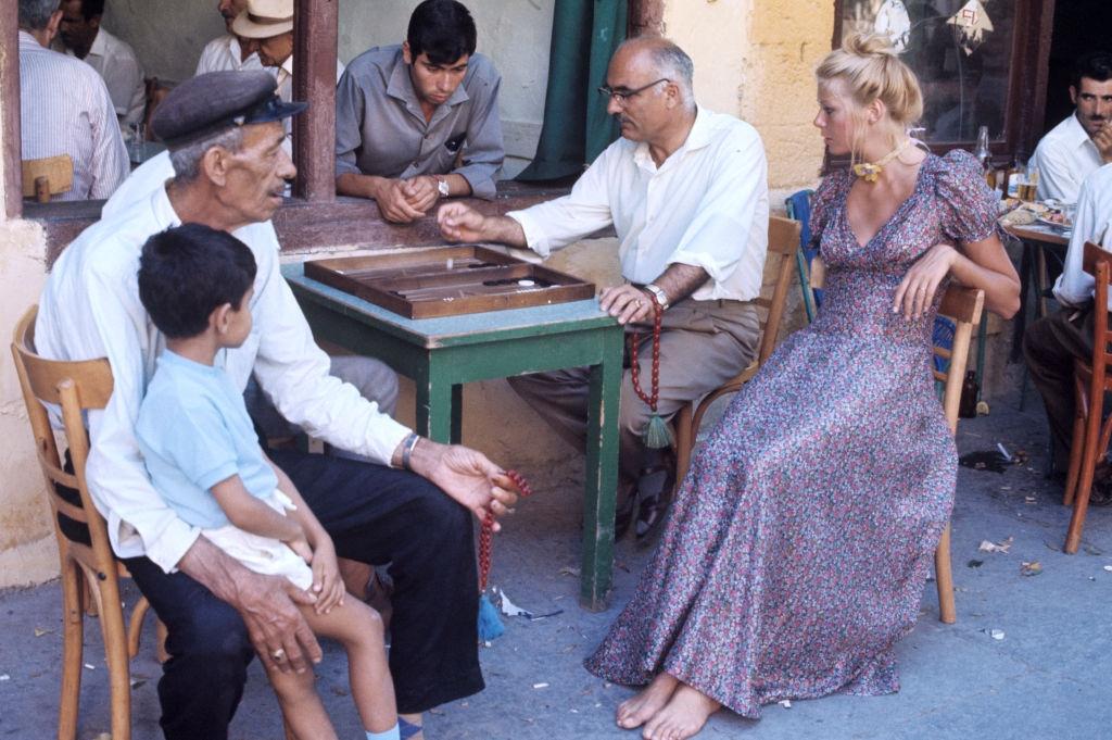 A young woman attends a game of jaquet played by locals at a terrace in the old town in Rhodes, 1971.