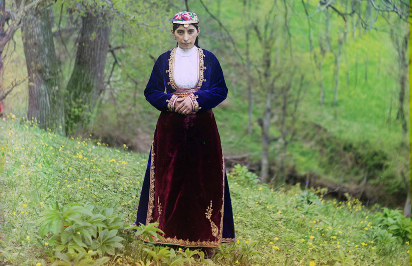 An Armenian woman in national costume poses for Prokudin-Gorskii on a hillside near Artvin (in present day Turkey), 1910.