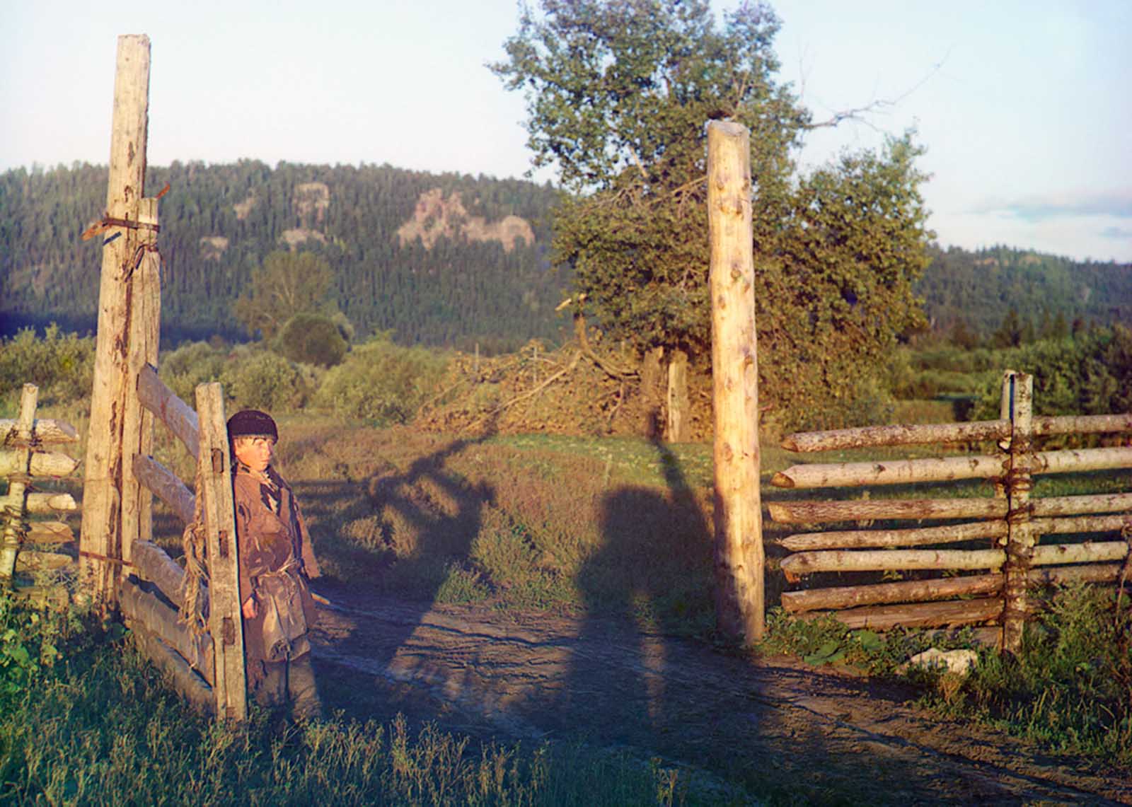 A boy leans on a wooden gatepost in 1910. From the album “Views in the Ural Mountains, a survey of an industrial area, Russian Empire