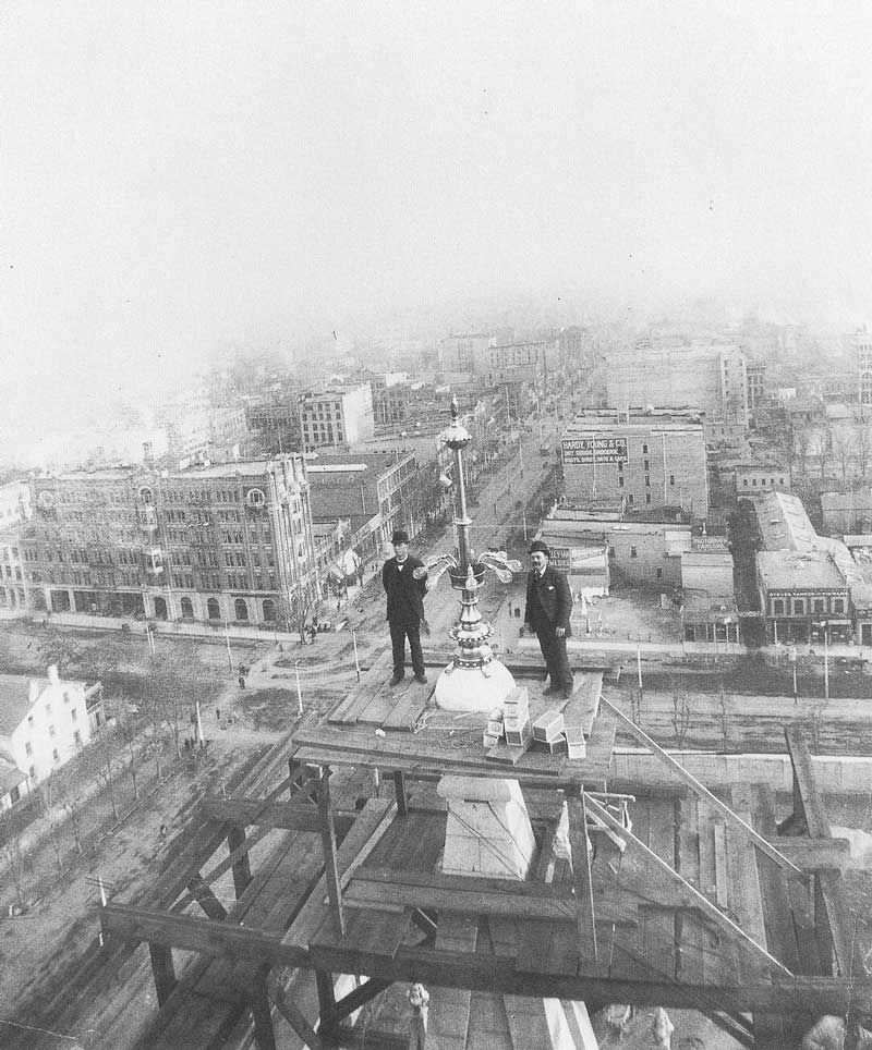 George Albert Smith and temple electrician Ephraim Holding install electric lights on the copper finials on the southeastern tower of the temple.