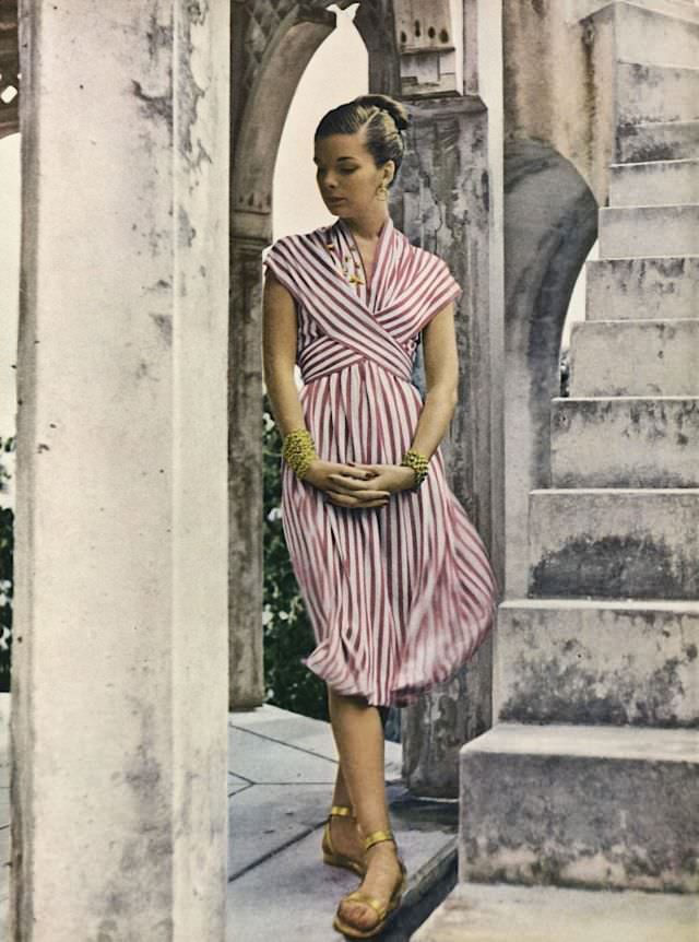 Model is wearing striped rayon jersey dress with wrapped bodice by Mildred Orrick, Vogue, 1946