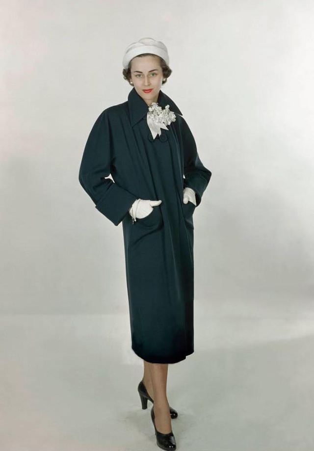 Model Joan Petit wearing navy, worsted wool coat by Lassie Maid and Madcaps’ pique hat in white, Glamour, 1948