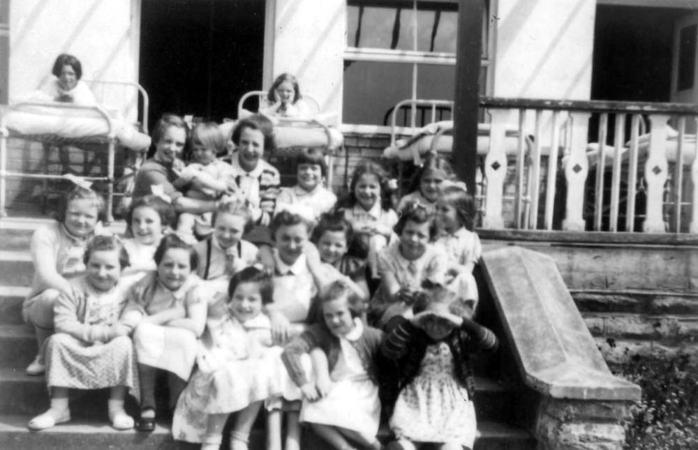 A nurse with a crowd of young patients on steps of Brough Ward (infant and younger girls) at Stannington Sanatorium in the summer of 1953.
