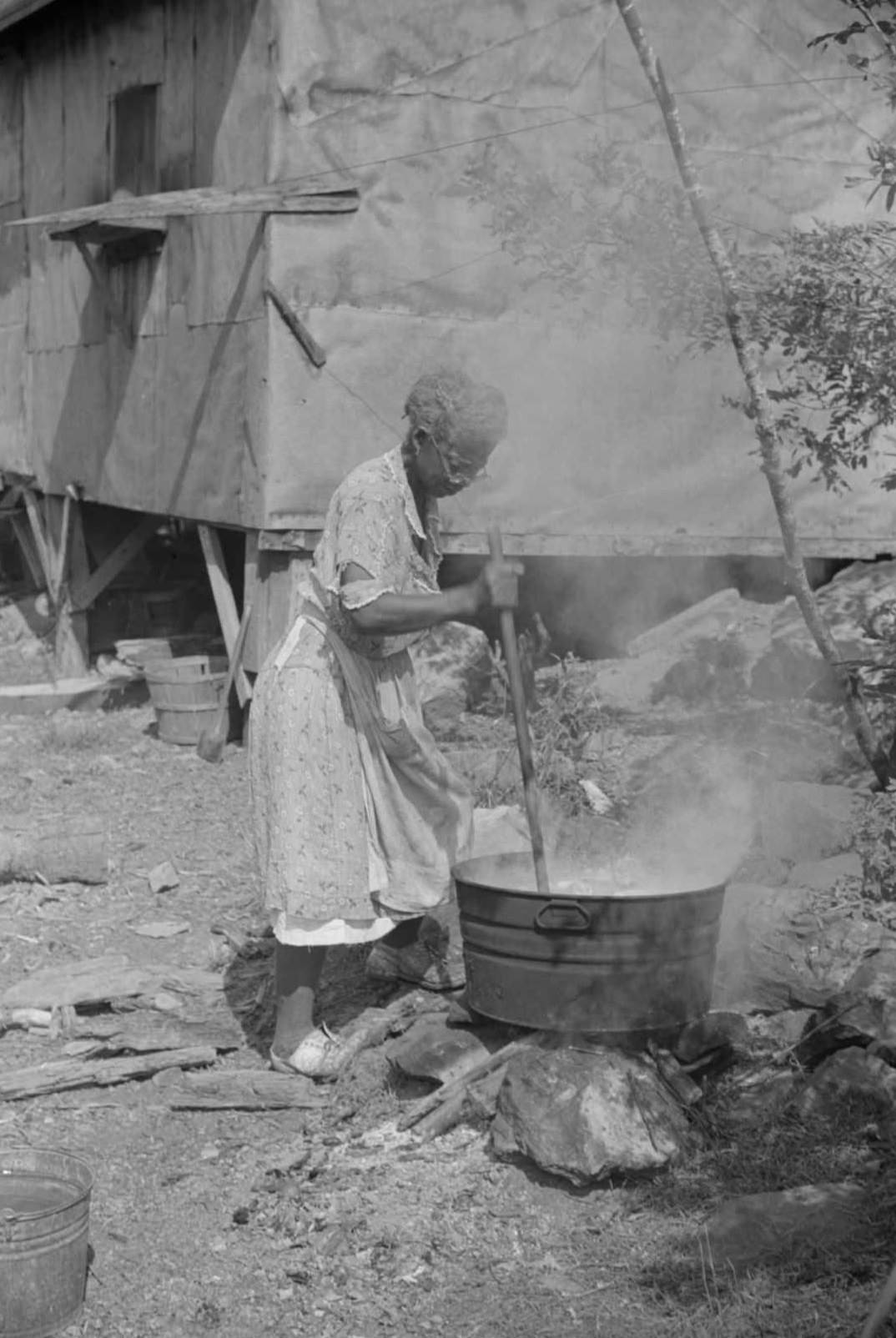Woman washing clothes outside of shacks along the river, on the highway between Charleston and Gauley Bridge, West Virginia, 1938.