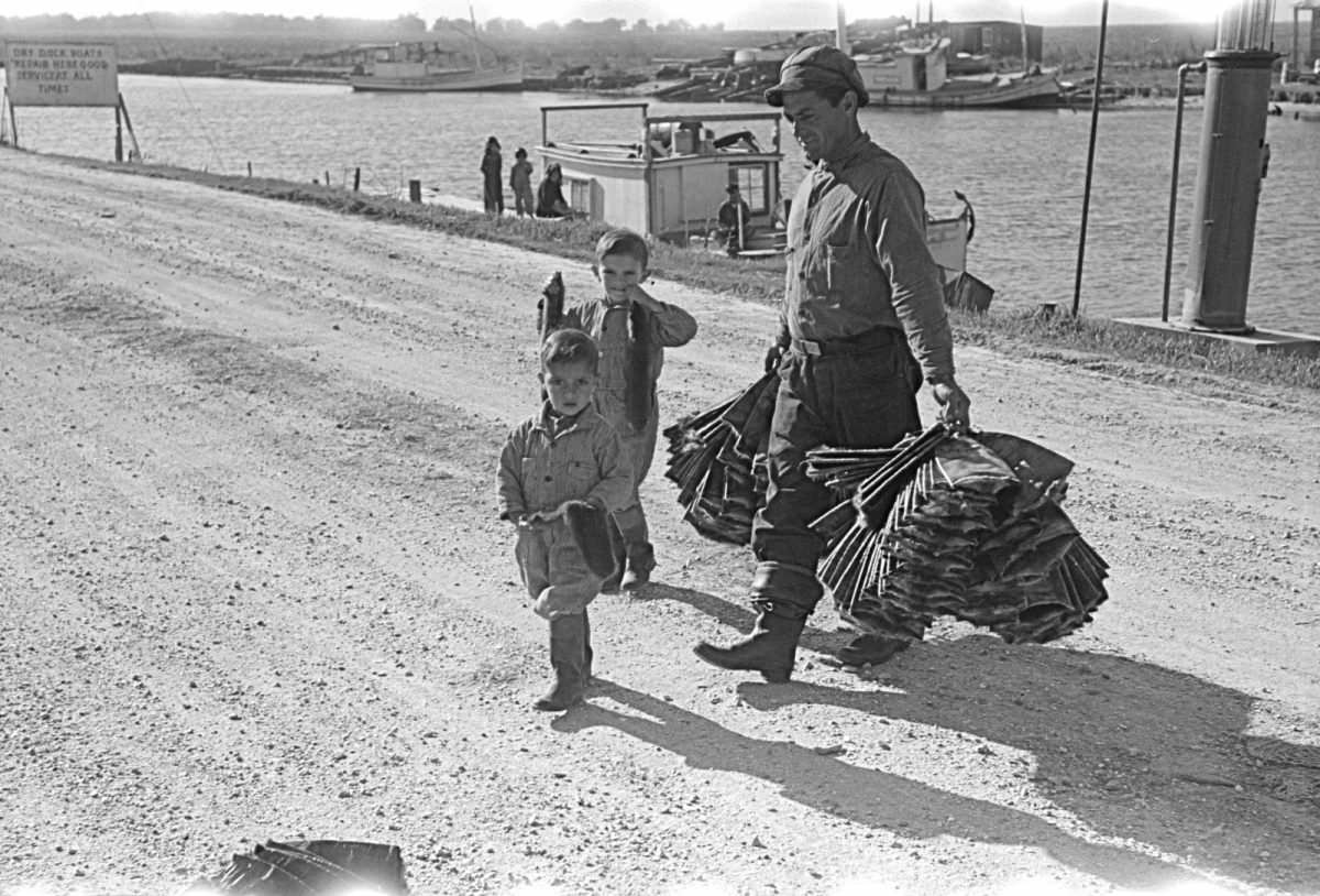 A trapper and his children taking muskrat pelts into the FSA (Farm Security Administration) auction sale held in a dancehall on Delacroix Island, Louisiana, 1941.