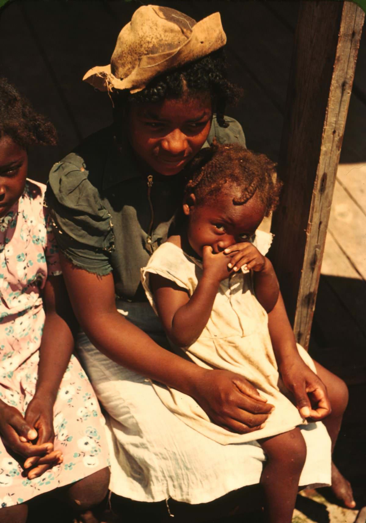 Three children sitting on the porch of a house, 1940.