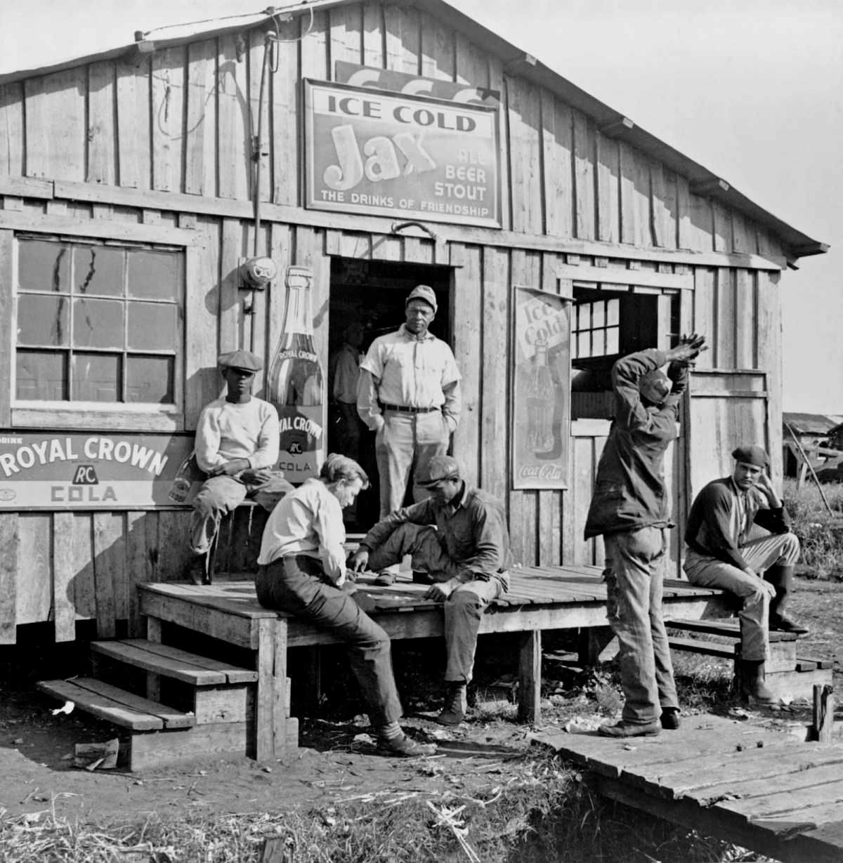Migratory laborers playing checkers in front of a ‘jook joint’ during slack season for vegetable pickers. Belle Glade, Florida, 1941.
