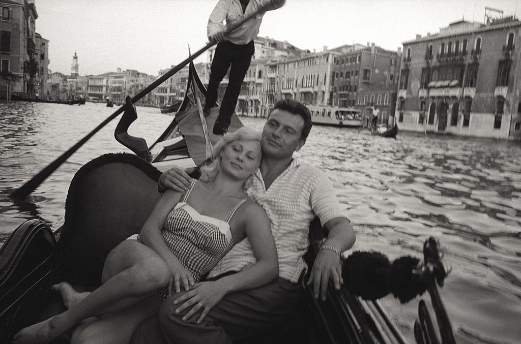 Abbe Lane dancing on the roof of a boat, encircled with admirers during the 17th Venice Intenational Film Festival. Venice , 1956.