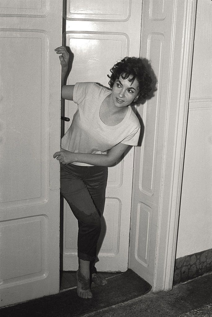 The actress Gina Lollobrigida pokes her head out the door of her hotel room, wet trousers and sanded feet, after going to the beach, during the 17th Venice Intenational Film Festival.