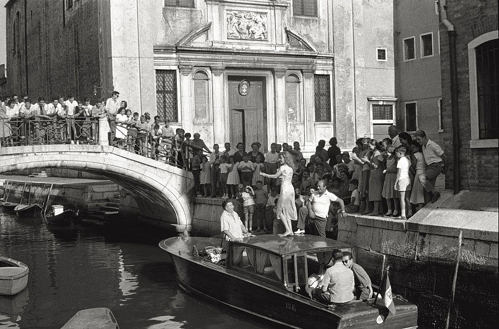 The actress Abbe Lane dancing on the roof of a boat, encircled with admirers during the 17th Venice Intenational Film Festival.