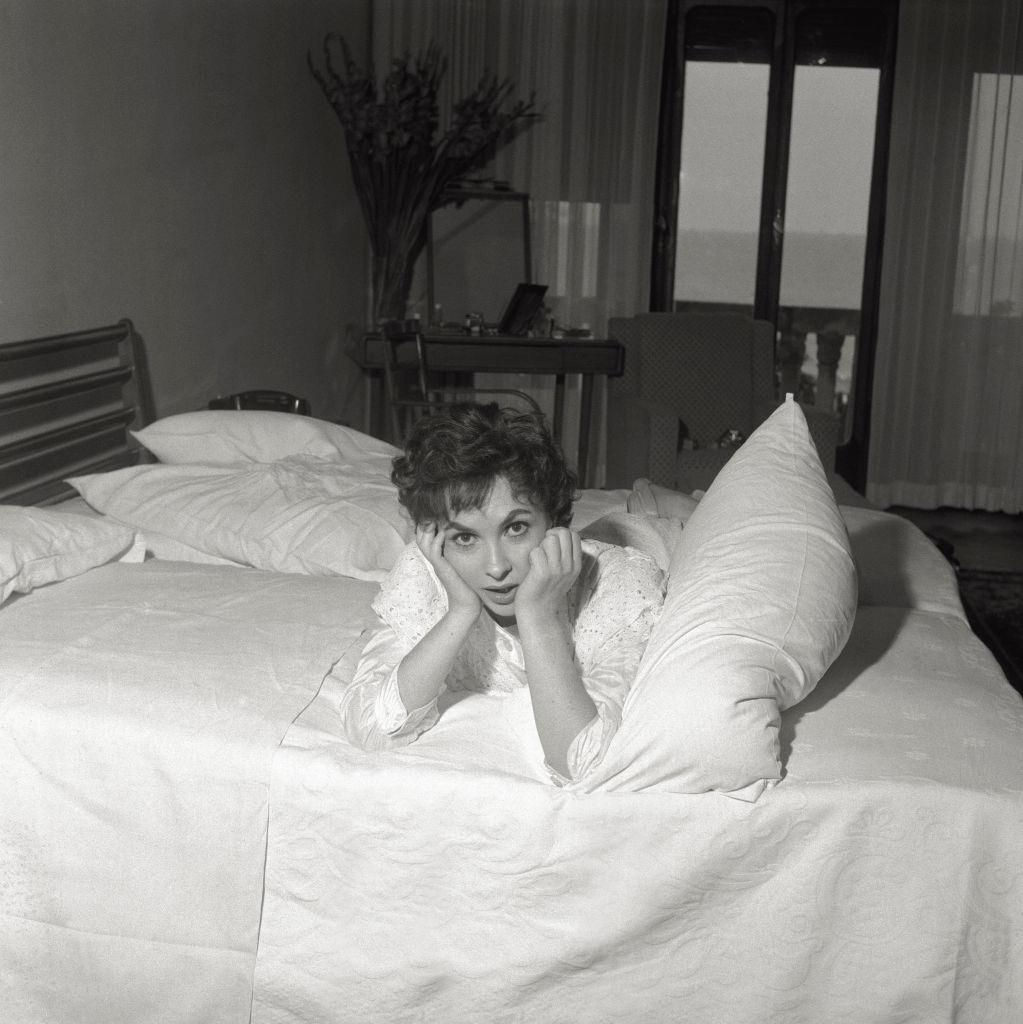 The actress Gina Lollobrigida comfortably lies in a hotel's room bed, during the 17th Venice Intenational Film Festival.