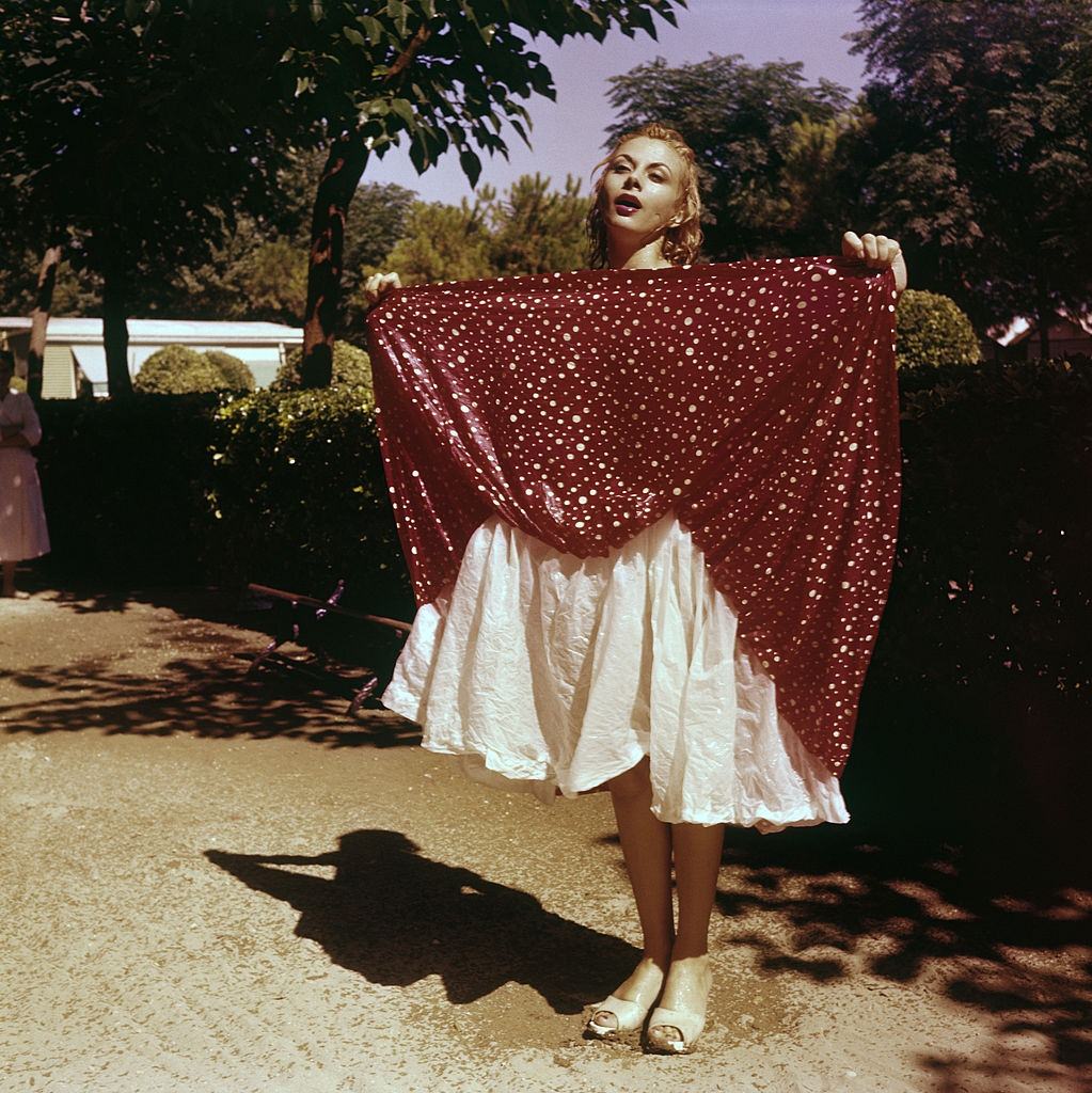 Italian actress and TV presenter Sandra Milo (Salvatrice Elena Greco) lifting up the wet skirt of her dress.