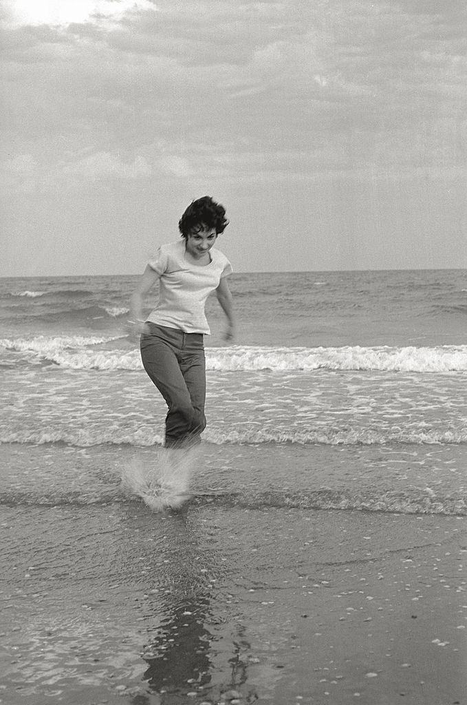 The actress Gina Lollobrigida on the seashore, her feet in the water, during the 17th Venice Intenational Film Festival. Venice (Italy), 1956.