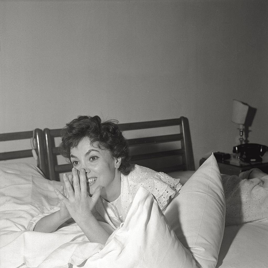 The actress Gina Lollobrigida jokes, lying on the bed of her hotel room, during the 17th Venice Intenational Film Festival.