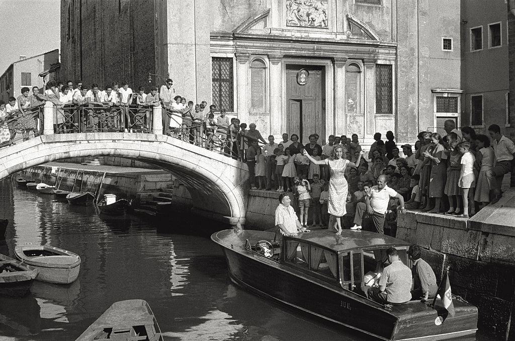 The actress Abbe Lane dancing on the roof of a boat, encircled with admirers during the 17th Venice Intenational Film Festival.