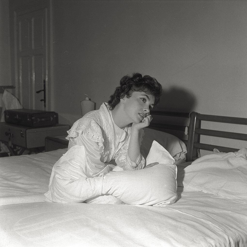 Lost in her thoughts, the actress Gina Lollobrigida sits on the bed of her hotel room, during the 17th Venice Intenational Film Festival.