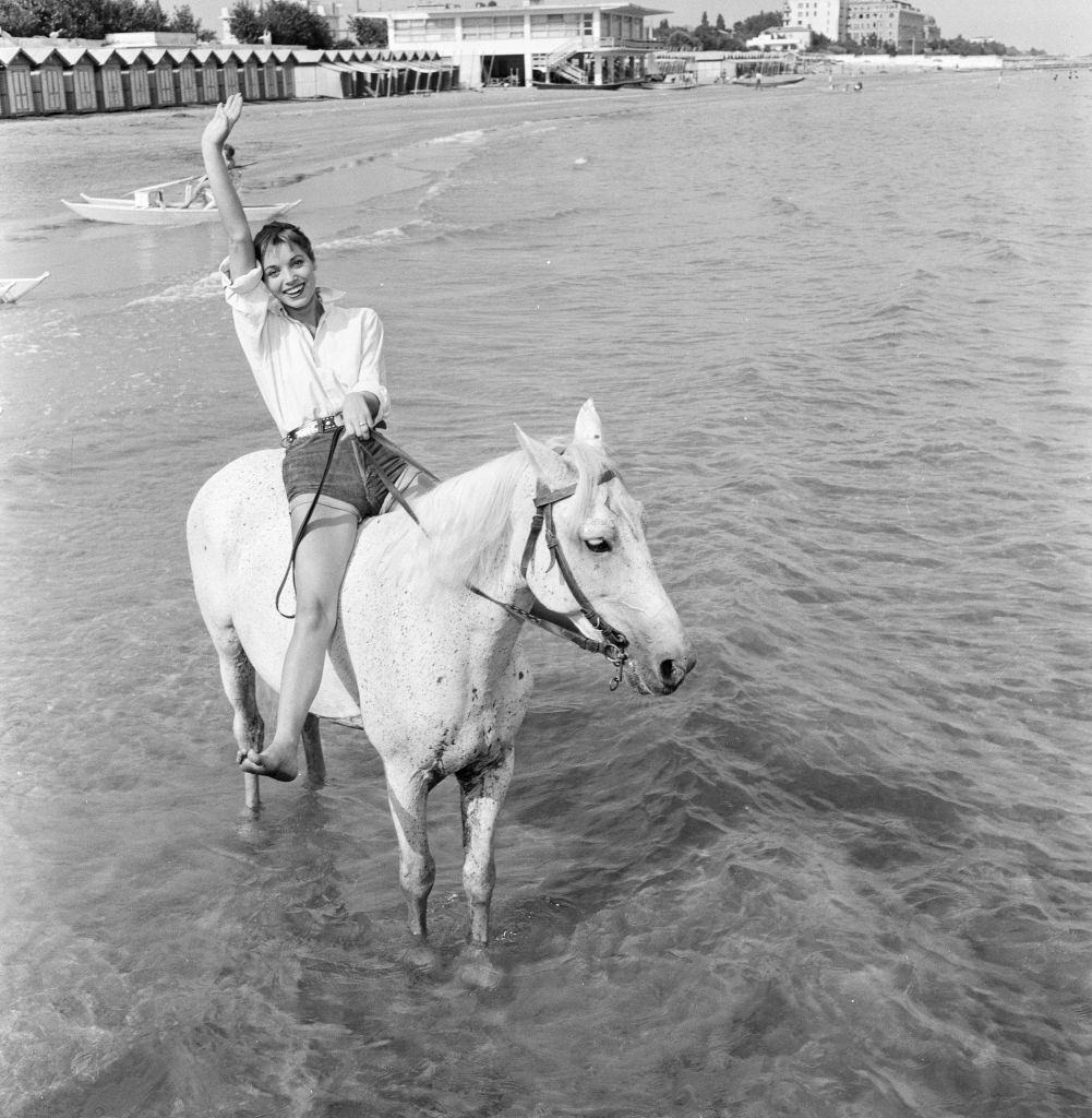 Italian actress and fashion model Elsa Martinelli enjoys a ride in the sea on Bill the horse.