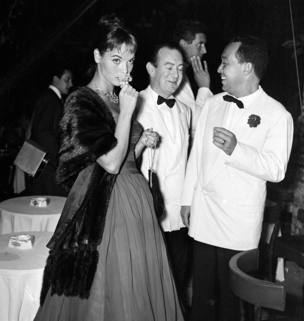 Italian actress Elsa Martinelli smelling flower, in background, Bernard McElwaine Sunday Pictorial Journalist.