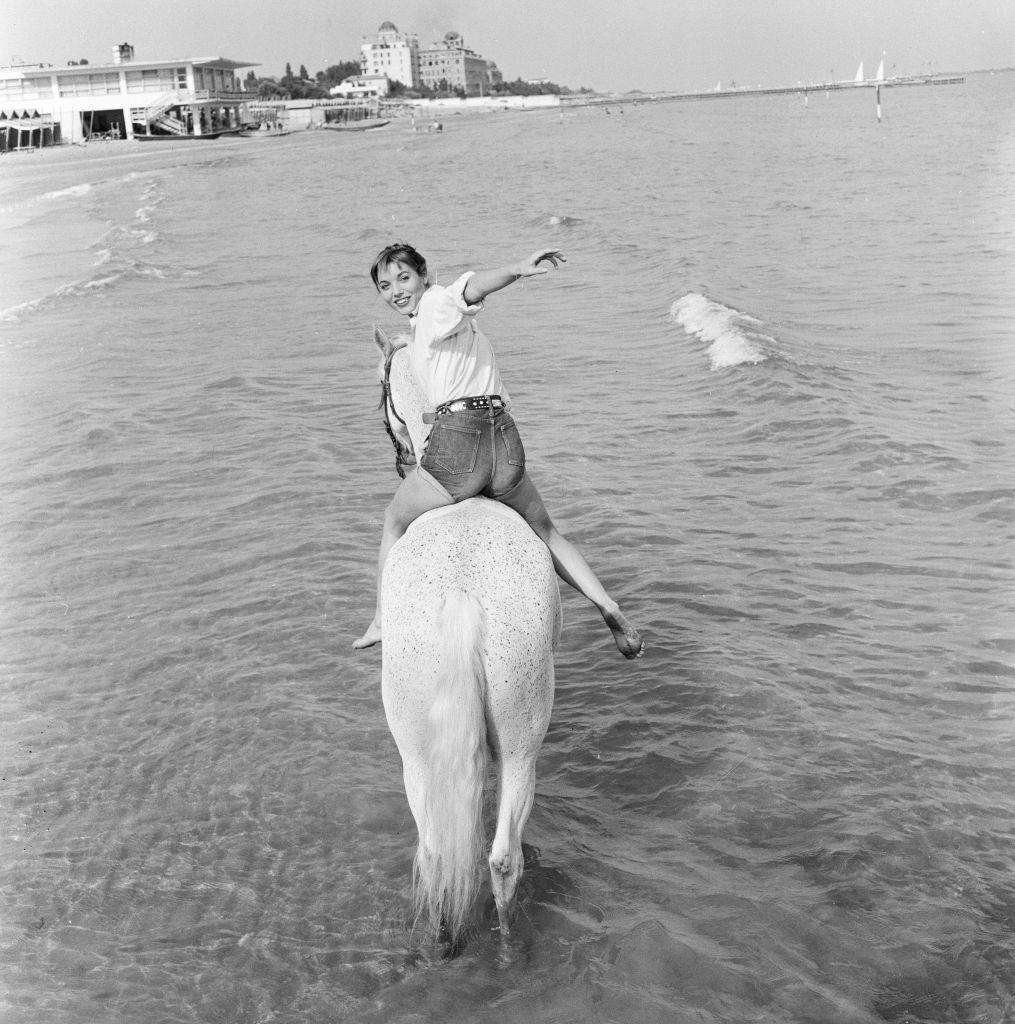 Italian actress and fashion model Elsa Martinelli enjoys a ride in the sea on Bill the horse.