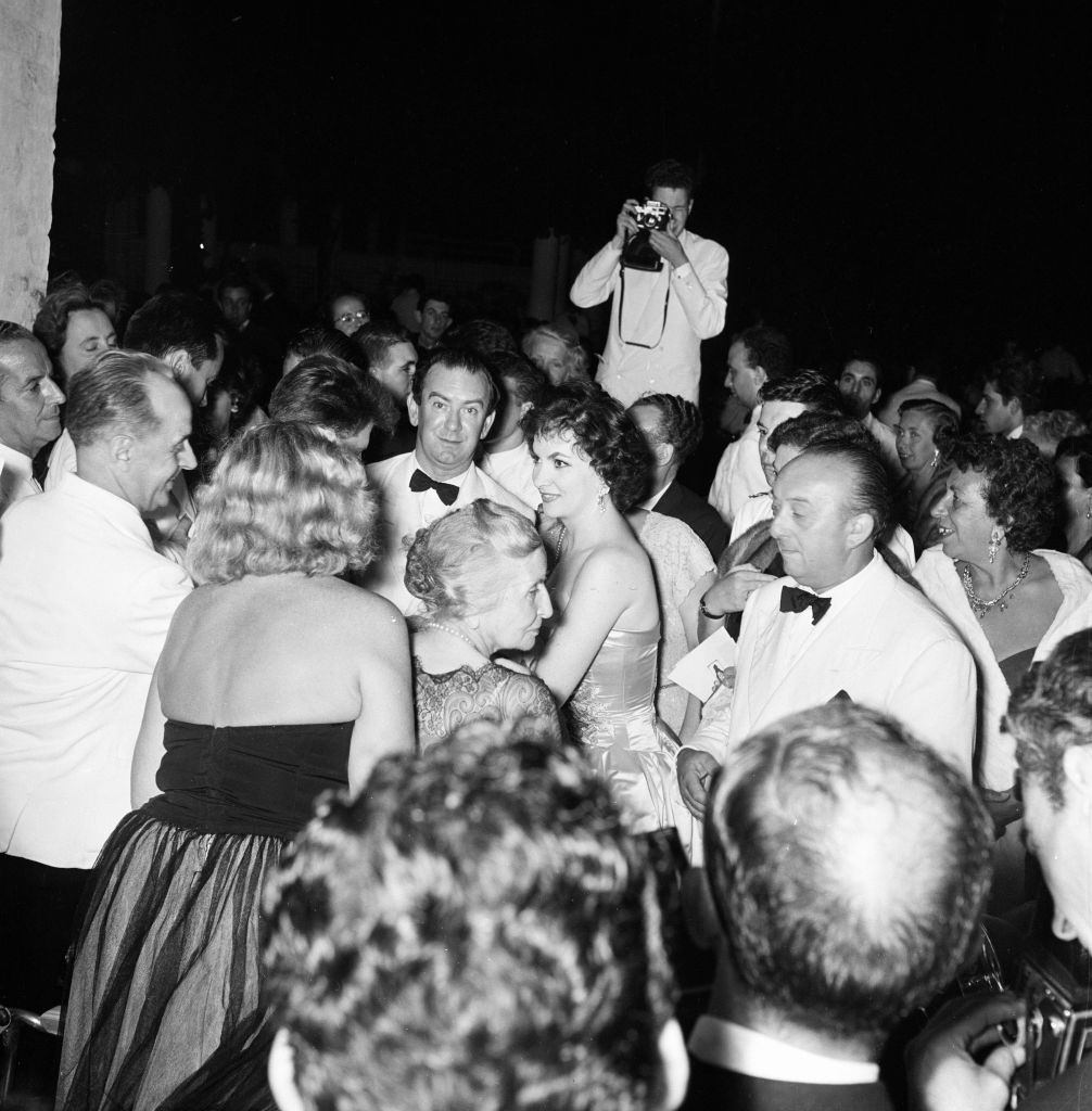 Italian actress Gina Lollobrigida arrives at the festival theatre, also, looking towards camera, Bernard McElwaine Sunday Pictorial Journalist.