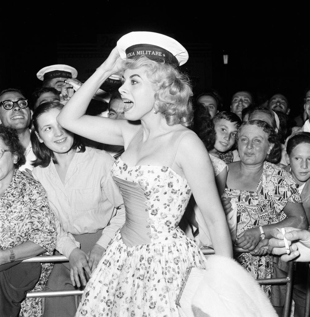 Italian actress Sandra Milo arrives at the Casino, applauded by fans and a member of the Italian navy at 1956 Venice Film Festival.