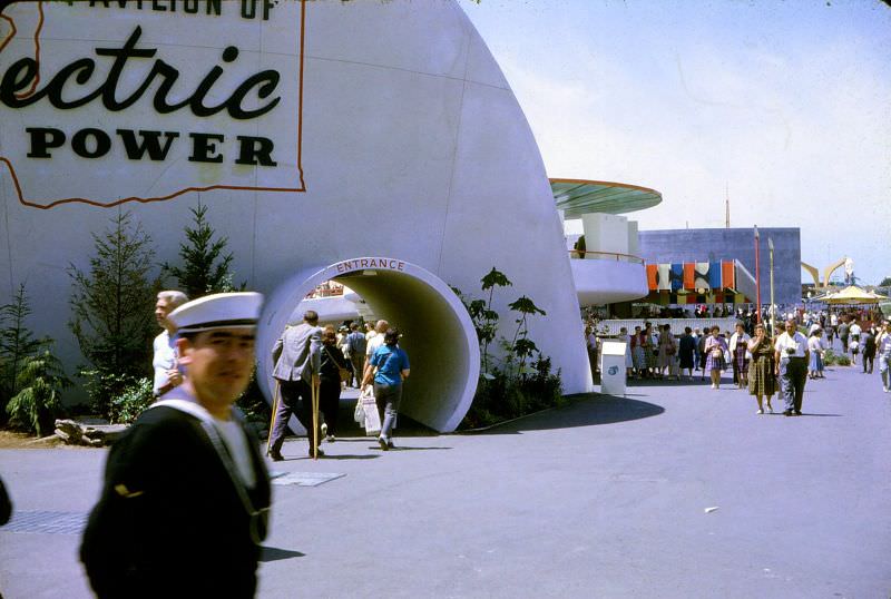 A sailor walks by as a man on crutches enters the Pavilion of Electric Power at the 1962 Seattle World's Fair
