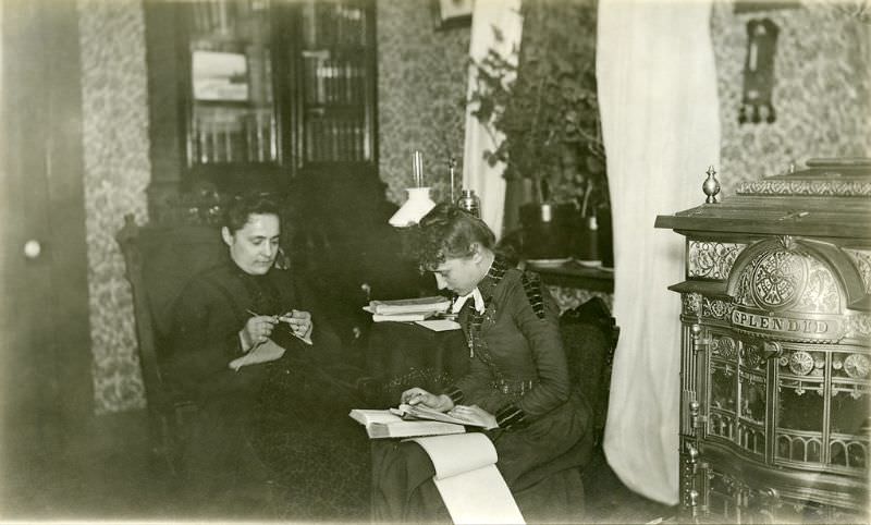 Katherine Horack knits in the Horack family parlor, while Bertha Shambaugh, her daughter, appears to be copying or taking notes from a book on her lap, circa 1897-1905