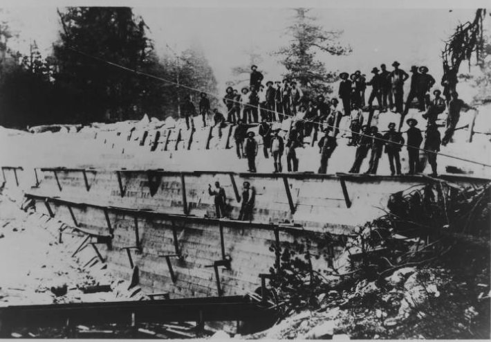 The construction of the original timber faced, rock-filled dam that impounded the millpond for C.B. Shaver's pioneer lumbering venture at Shaver Lake 1893