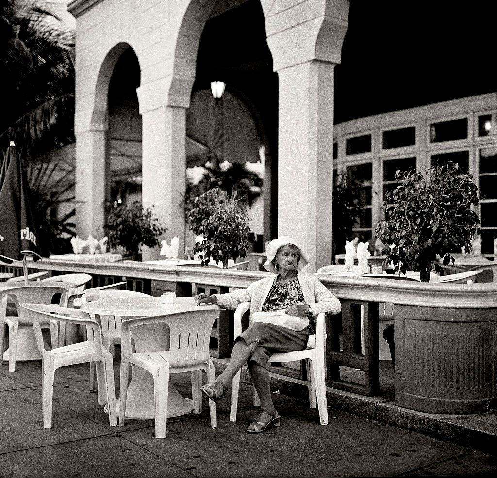 Elderly woman resting outside a cafe on Ocean drive, Miami Beach.