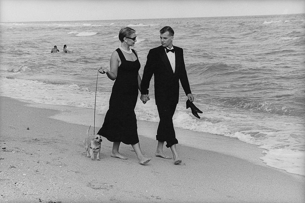 A couple in formalwear strolling hand-in-hand on Miami Beach, Florida, 1990s.