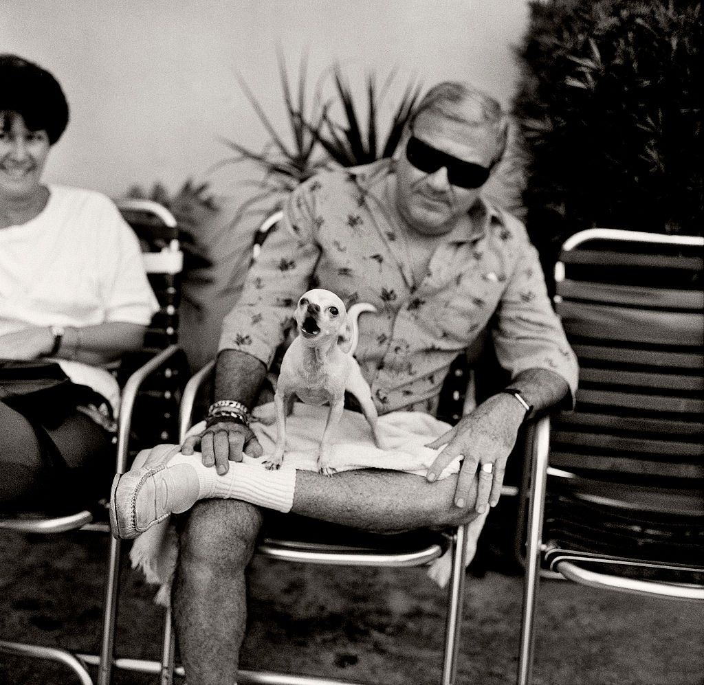 Man with angry dog sitting on hotel veranda on Collins Avenue, Miami Beach, Florida.