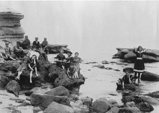 Children and adults in bathing suits on the rocks at La Jolla beach, 1897