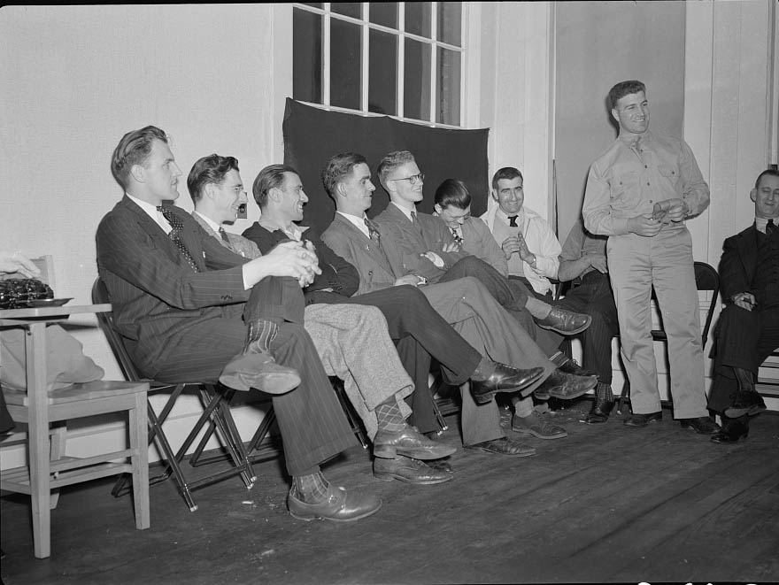 A group of young men soon to leave for army induction camps are listening to William Mongelo, of the U.S. Army Air Corps,1942