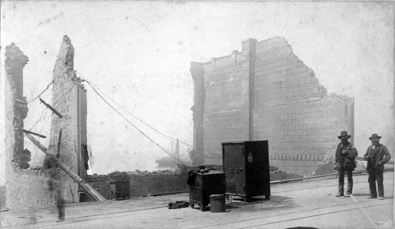 Two safes and two men in front of ruins of the Cracker Factory, 1889