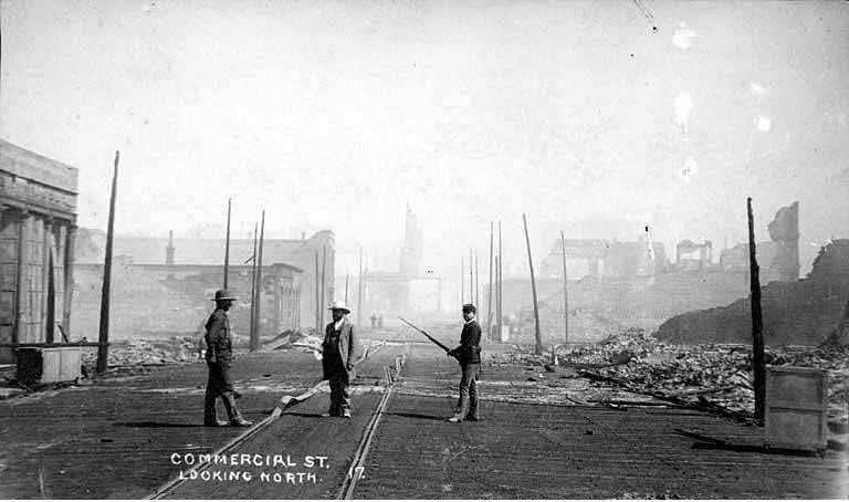 Looking north on Commercial St. showing a member of the Washington National Guard and two men, 1889
