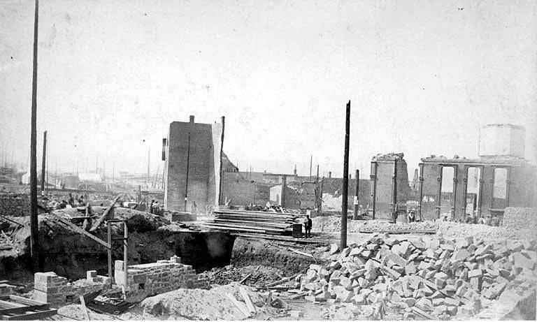 Lumber and ruins along Front St, 1889