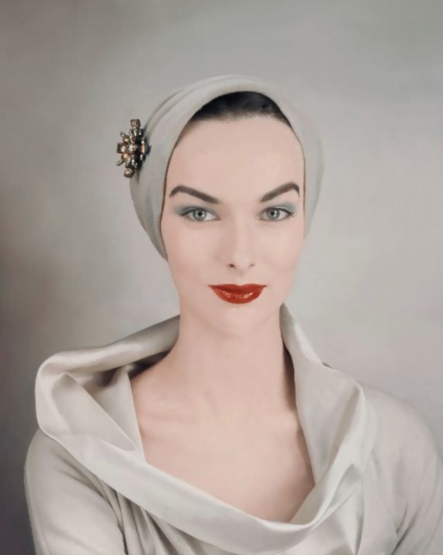 Victoria von Hagen wearing beige close fit turban pinned with diamond and amber brooch and cowl neck beige silk blouse, October 1952