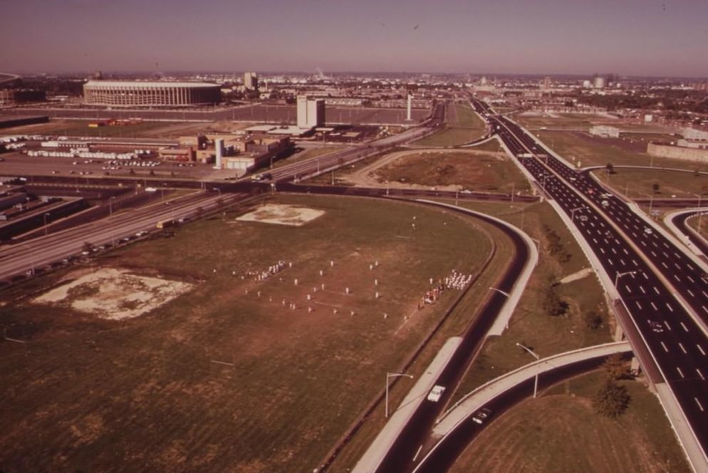 Junior High School Football Team Plays On Field Surrounded By Freeways. Municipal Stadium In Left Background, August 1973