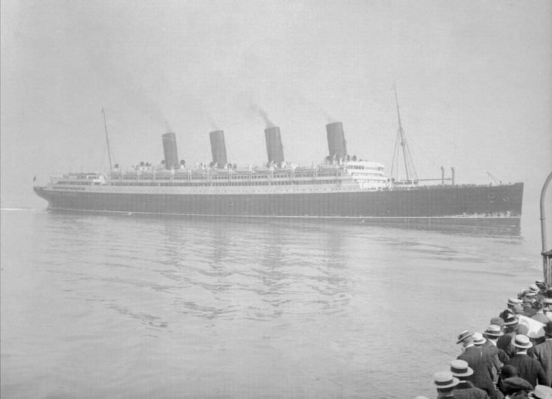 On a misty June morning, disembarking passengers crowd the rail of their tender for a last look at Aquitania, making her maiden call at the Welsh port Fishguard on June 16, 1914