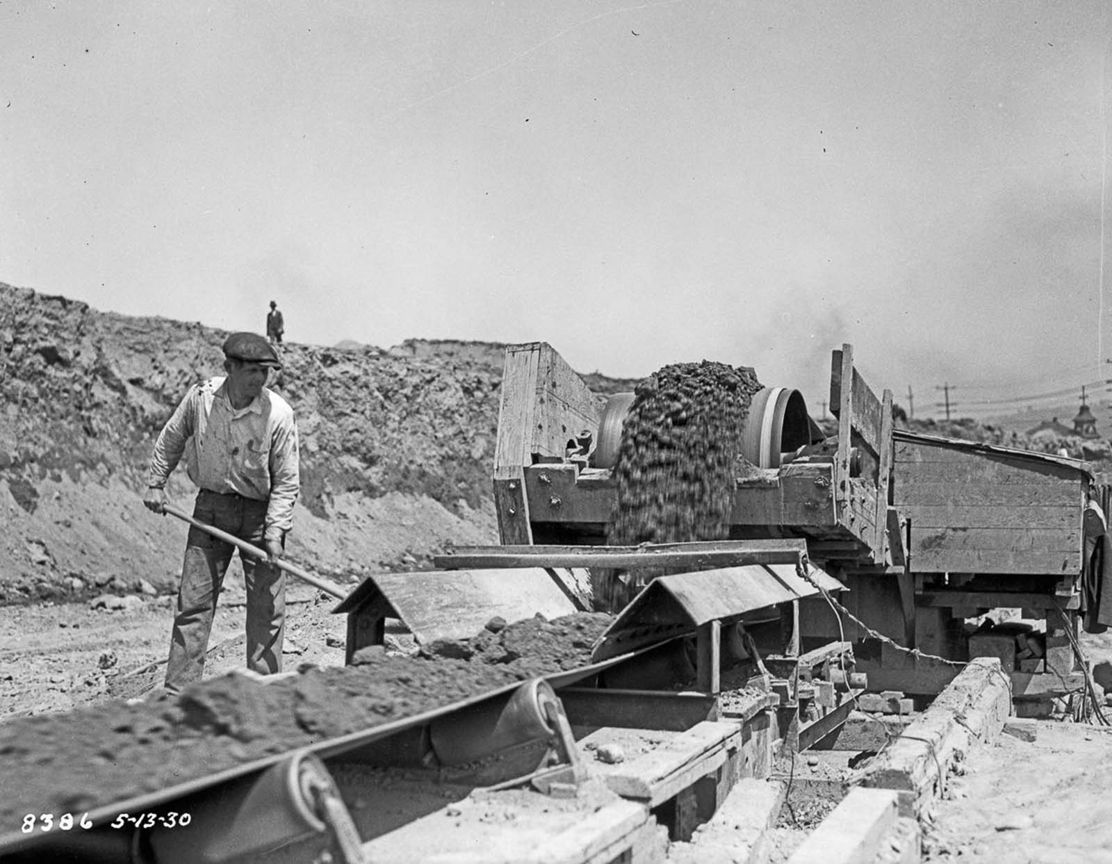 A conveyor belt carries earth from the dig site to the harbor. 1930.